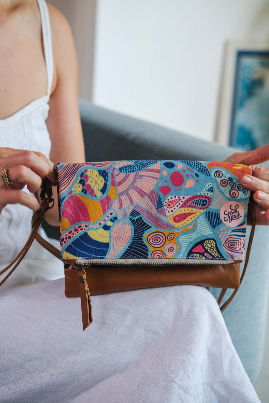 Close-up of the LeMerch Clutch, featuring an original artistic print, leather trim, and zipper.
