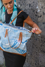 Model wearing the LeMerch TENCEL™ Square Scarf wrapped in her head and closing the LeMerch tote bag featuring an original artistic print.