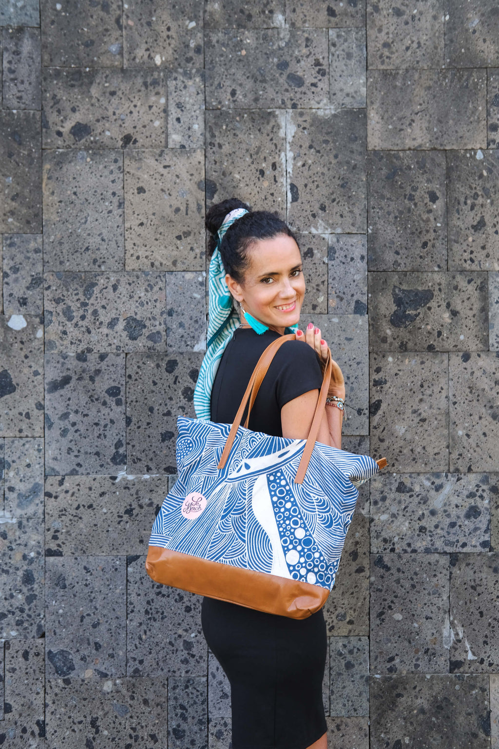 Model holding the LeMerch Tote Bag, featuring an original artistic print and leather trim.