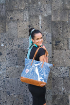 Model holding the LeMerch Tote Bag, featuring an original artistic print and leather trim.