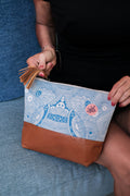 Close-up of the LeMerch Essential Pouch featuring an original artistic print, leather trim, and zipper.