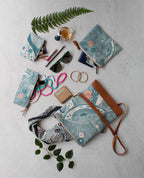Collection of blue patterned pouches, and accessories on a light gray surface.