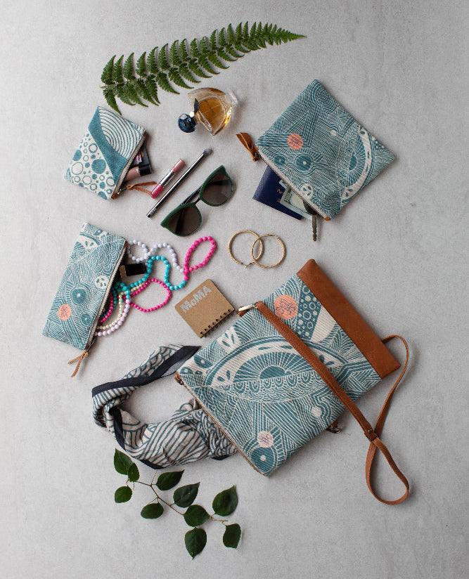 Collection of blue patterned pouches, and accessories on a light gray surface.