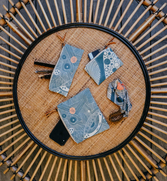 Set of blue patterned pouches on a woven mat with wooden background